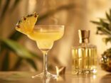 Gin mit Ananassaft in einem eleganten Glas garniert mit einer Ananasscheibe und Minzblättern