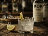 Flasche Roku Gin auf rustikalem Holztisch, umgeben von Botanicals, perfekt für eine detaillierte Roku Gin Bewertung