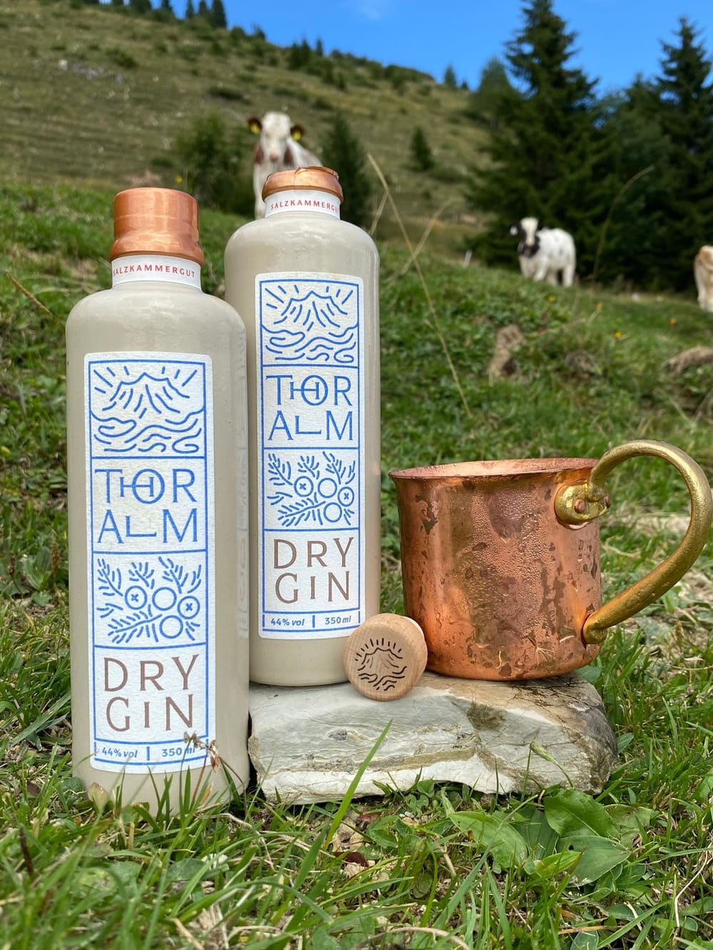 Der Thoralm Gin mit einer Tasse am Berghang.